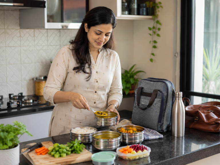 Indian professional packing a balanced tiffin with dal, rice, sabzi, fruit, and vegetables for work.